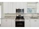 A bright kitchen featuring white cabinets, stainless steel appliances, and granite countertops at 4237 Marine Pkwy, New Port Richey, FL 34652