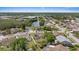 Wide aerial view featuring a neighborhood layout near a lake with homes, mature trees, and manicured lawns at 5412 Merkin Pl, New Port Richey, FL 34655
