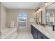 Bright bathroom with double sinks, a soaking tub, a large window, and a modern vanity with ample storage at 5412 Merkin Pl, New Port Richey, FL 34655
