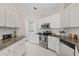 Bright kitchen with stainless steel appliances, granite countertops, white cabinets, and adjacent laundry room at 5412 Merkin Pl, New Port Richey, FL 34655