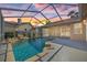 Relaxing pool area at dusk with rock waterfall feature and screened enclosure to protect the pool and decking at 5412 Merkin Pl, New Port Richey, FL 34655