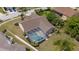 Aerial shot of backyard oasis with a sparkling screened-in pool, surrounded by manicured landscaping and a privacy fence at 5412 Merkin Pl, New Port Richey, FL 34655