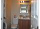 A small bathroom with a stacked washer and dryer next to a toilet and vanity with mirror at 6037 Chesham Dr # 3, New Port Richey, FL 34653