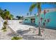 Backyard view of a light blue house with gray stone paver patio, white privacy fence, and palm trees in the yard at 7221 Westwind Dr, Port Richey, FL 34668