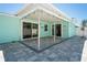Backyard featuring a light blue exterior, covered patio, and gray-toned pavers at 7221 Westwind Dr, Port Richey, FL 34668