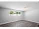 Well-lit bedroom with gray wood-look flooring and a bright window overlooking the yard at 7221 Westwind Dr, Port Richey, FL 34668