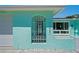 Charming turquoise home with decorative bars, arched entryway and address numbers at 7221 Westwind Dr, Port Richey, FL 34668