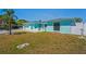 Turquoise home with well-maintained landscaping, white fence and decorative front gate at 7221 Westwind Dr, Port Richey, FL 34668