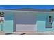 Exterior garage view with a white garage door, light blue paint, and barred window at 7221 Westwind Dr, Port Richey, FL 34668