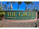 Community sign for The Groves Golf & Country Club, surrounded by palm trees and lush landscaping at 7511 Melogold Cir, Land O Lakes, FL 34637
