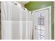 Bathroom showcasing a decorative glass door, shower with a curtain, and green and white walls at 7925 Calindra Ct, Trinity, FL 34655