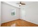Bright bedroom featuring a ceiling fan, wood-look floors, a large window, and a white door at 7925 Calindra Ct, Trinity, FL 34655