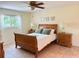 This bedroom features a ceiling fan and warm-toned tile floors with a wooden sleigh bed and matching nightstands at 9348 Villa Entrada, New Port Richey, FL 34655