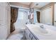 Bright bathroom with tile floors and white cabinets; shower-tub combo with curtain and modern fixtures at 9636 Brookdale Dr, New Port Richey, FL 34655