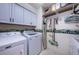 Efficient laundry room with white appliances, storage cabinets, and shelving for organized cleaning supplies at 9636 Brookdale Dr, New Port Richey, FL 34655