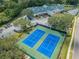 Aerial view of two tennis courts next to the community center, surrounded by trees and parking at 9636 Brookdale Dr, New Port Richey, FL 34655