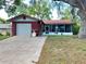 Charming home with a red brick facade, attached garage, and a screened-in porch at 10619 Mira Vista Dr, Port Richey, FL 34668