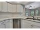Bright kitchen with stainless steel dishwasher and a view into the adjacent room at 11379 Flower Ave, Weeki Wachee, FL 34613