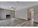 Spacious living room with a cozy fireplace, wood-look floors, and a ceiling fan for added comfort at 11379 Flower Ave, Weeki Wachee, FL 34613