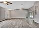 Spacious living room featuring wood-look tile floors, a ceiling fan, and access to a sliding glass door at 11379 Flower Ave, Weeki Wachee, FL 34613