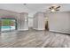 A large living area with sliding glass doors to the pool, wood-look floors, and an open layout to the kitchen at 11379 Flower Ave, Weeki Wachee, FL 34613