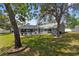 Lush backyard showcasing the pool, covered patio, fence, and mature trees, perfect for relaxing or entertaining at 1156 Battersea Ave, Spring Hill, FL 34609