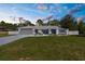 Charming single-story home with a well-manicured lawn, gray exterior, and an attached two-car garage at dusk at 1156 Battersea Ave, Spring Hill, FL 34609