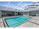 Inviting screened-in pool area featuring a sparkling pool and entertainment space with outdoor furniture at 1156 Battersea Ave, Spring Hill, FL 34609