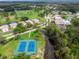 An aerial view of a neighborhood with mature trees, a golf course, tennis courts and a body of water at 12037 Boynton Ln, New Port Richey, FL 34654