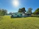 A backyard with a well-maintained lawn, mature trees, and a screened porch at 12037 Boynton Ln, New Port Richey, FL 34654