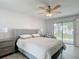 Comfortable main bedroom featuring light wood flooring, a ceiling fan, and a gray upholstered bed frame at 12087 Tallwood St, Spring Hill, FL 34608