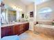 Large bathroom featuring dual sinks, a tub, tile flooring, and a large mirror at 1218 Castle Ter, Tarpon Springs, FL 34689