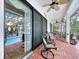 Relaxing covered patio with chairs, ceiling fans, and brick floors overlooks a screened-in pool for outdoor enjoyment at 1218 Castle Ter, Tarpon Springs, FL 34689