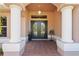 Elegant front entryway featuring double doors framed by decorative columns and a tiled porch at 12300 Drake Ln, Spring Hill, FL 34609