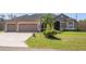 Charming home with a three-car garage, palm tree, decorative driveway, and manicured front yard at 12300 Drake Ln, Spring Hill, FL 34609