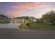 Inviting home with a three-car garage, well-kept lawn, palm tree, and decorative driveway at sunset at 12300 Drake Ln, Spring Hill, FL 34609