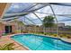 Beautiful in-ground swimming pool with blue-tiled trim, a screened enclosure, and a fenced backyard at 12300 Drake Ln, Spring Hill, FL 34609