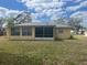Exterior view of the home's back featuring a screen porch and multiple windows at 1332 Inca Ave, Spring Hill, FL 34608