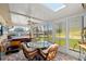 Enclosed sunroom featuring a glass-top dining table, brick floors, hot tub, and lots of windows with views of the canal at 13811 Michelle Ave, Hudson, FL 34667