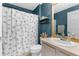 Cozy bathroom with stylish shower curtain, neutral vanity and blue painted walls at 14581 Wake Robin Dr, Brooksville, FL 34604