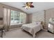Comfortable bedroom with a large window, ceiling fan, and decorative headboard at 14581 Wake Robin Dr, Brooksville, FL 34604