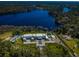 Stunning aerial view of estate home with tennis court, lush landscaping, and waterfront lake access at 18725 Jiretz Rd, Odessa, FL 33556