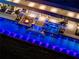 Overhead night view of a luxury pool with a unique design, illuminated with vibrant lights and a cozy fire pit lounge at 18725 Jiretz Rd, Odessa, FL 33556