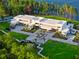Stunning aerial view of a modern luxury home with lush landscaping, a tennis court, and waterfront access at 18725 Jiretz Rd, Odessa, FL 33556
