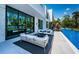 Modern patio with comfortable white couches, overlooking a stunning pool and lakeside view at 18725 Jiretz Rd, Odessa, FL 33556