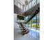 Modern staircase with glass railings, floating wood steps, and abundant natural light streaming through large windows at 18725 Jiretz Rd, Odessa, FL 33556