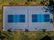 Aerial view of a blue and gray tennis court surrounded by palm trees and green lawns on a sunny day at 18725 Jiretz Rd, Odessa, FL 33556