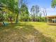 Lush backyard offering mature trees and ample space for recreation, enhanced by colorful Adirondack chairs at 24104 Peppermill Dr, Brooksville, FL 34601