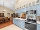 Open kitchen with blue cabinets, tile floors, stainless steel appliances, and dining area access at 24104 Peppermill Dr, Brooksville, FL 34601
