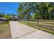 Long concrete driveway leading up to a two story home with a red garage door and mature trees at 28330 Peterson Camp Rd, Brooksville, FL 34601